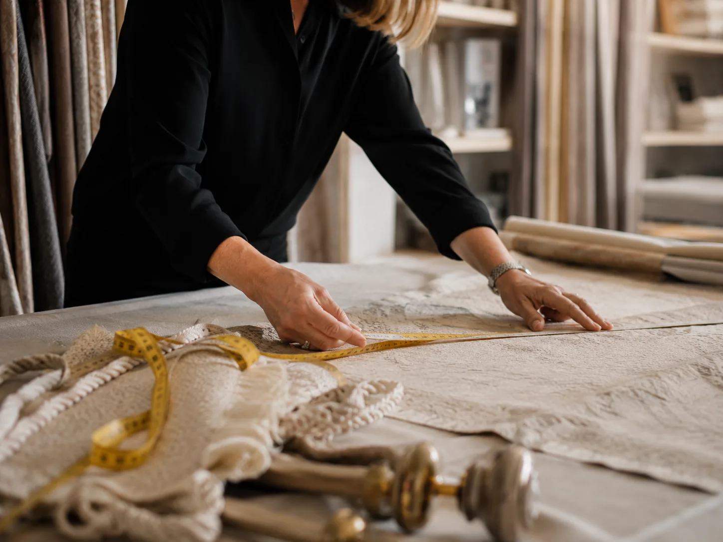 Professional carefully measuring fabric and trim in a window treatment workroom